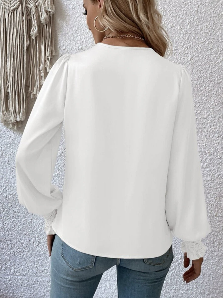 White ruched surplice blouse with long puff sleeves and smocked cuffs.