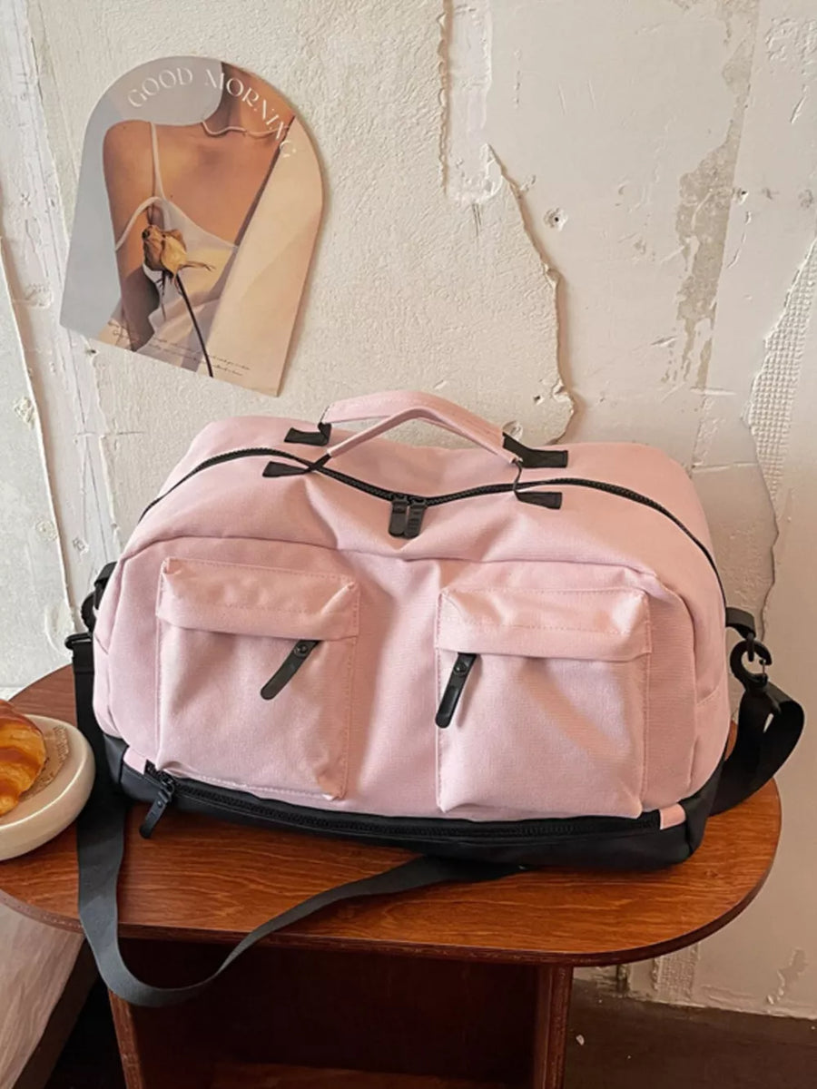 Pink duffle bag with two front zip pockets and black trim