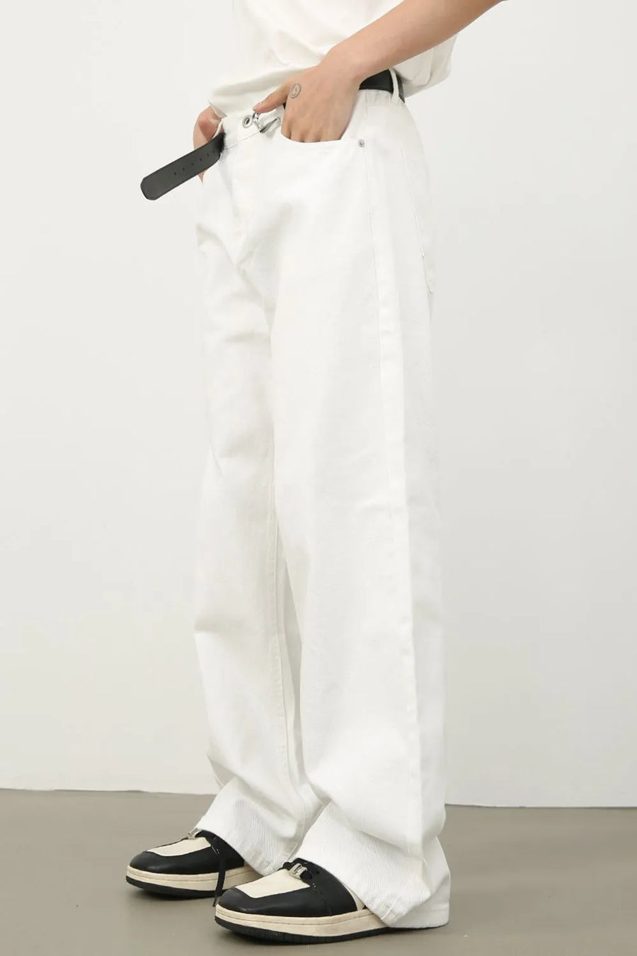 Sculpted wide leg denim trousers in ivory, styled with a belt and sneakers.
