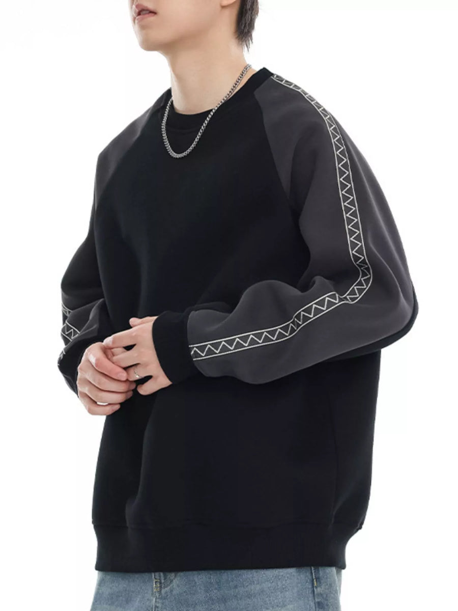 Black oversized raglan sleeve sweatshirt with gray contrast sleeves featuring white zigzag stitching detail.