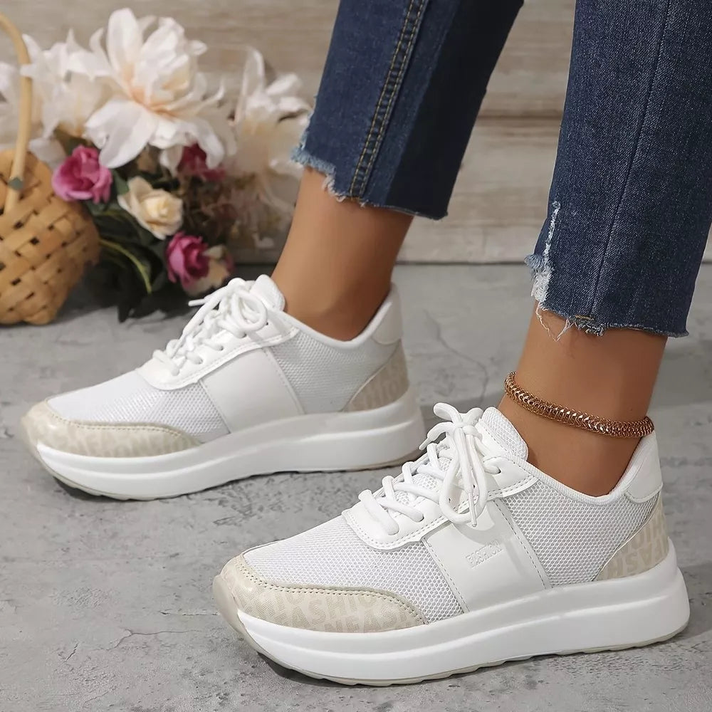 White lace-up sneakers with mesh panels and distinctive logo detailing on the sole.