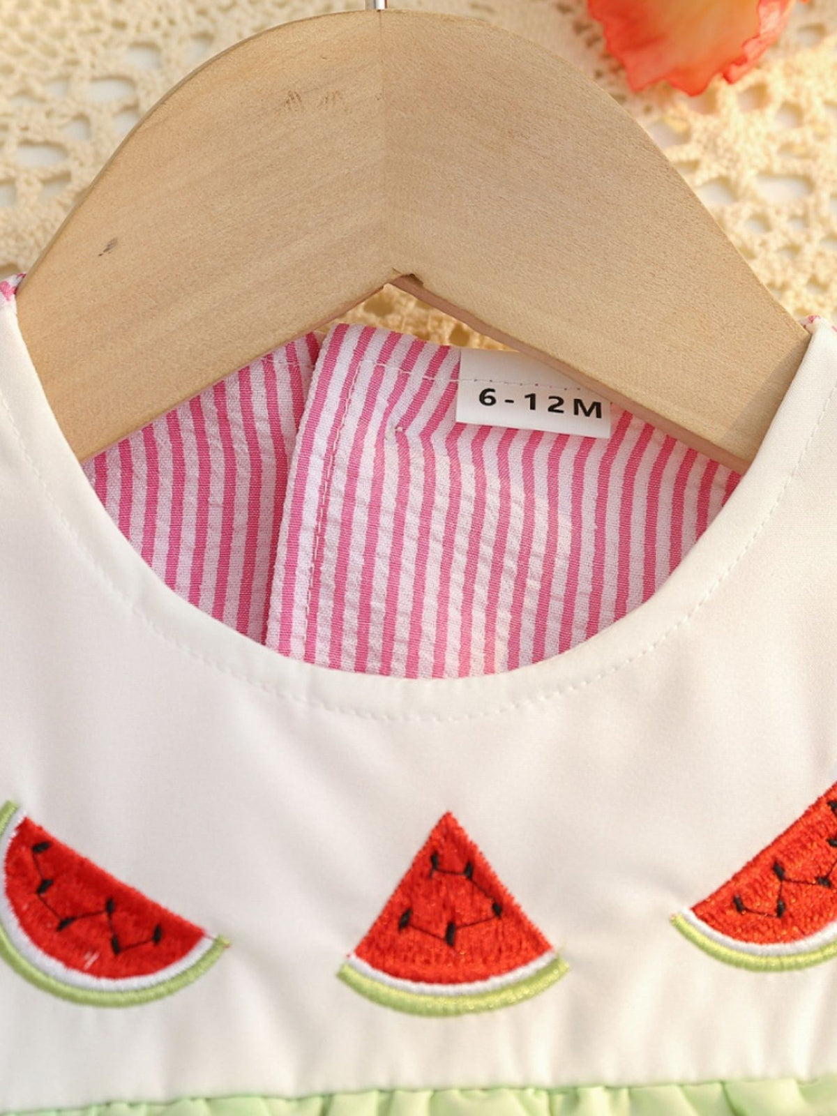 Baby dress with embroidered watermelon slices and pink stripe lining.