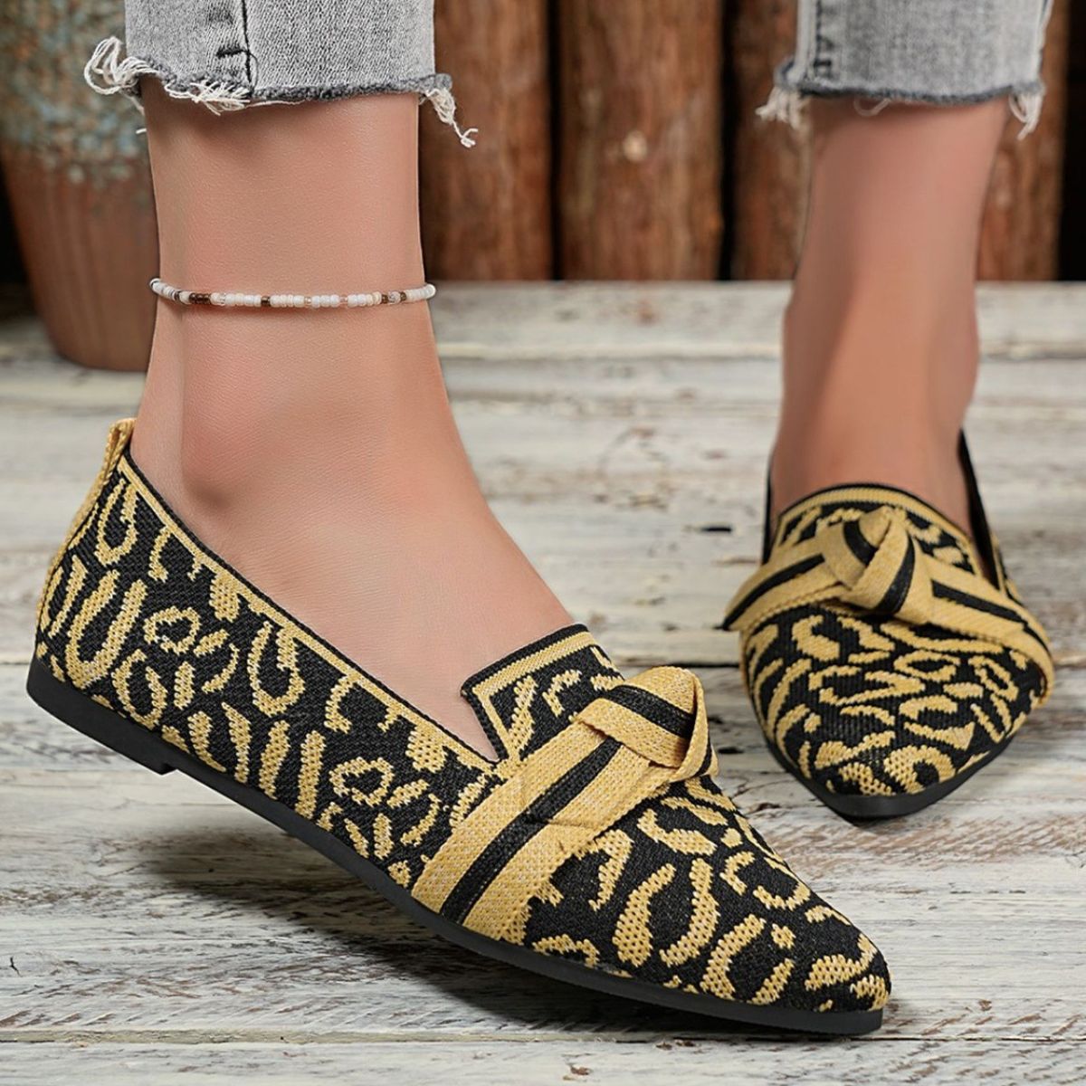 Knot detail point toe slip-ons in yellow and black abstract print.