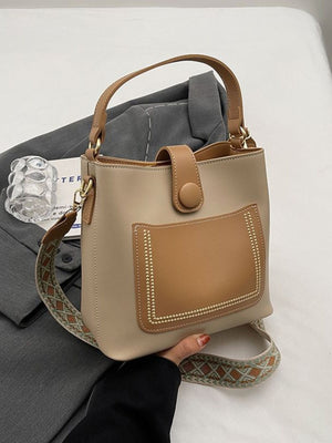 Medium pu leather bucket crossbody bag in brown with decorative stitching and patterned strap.