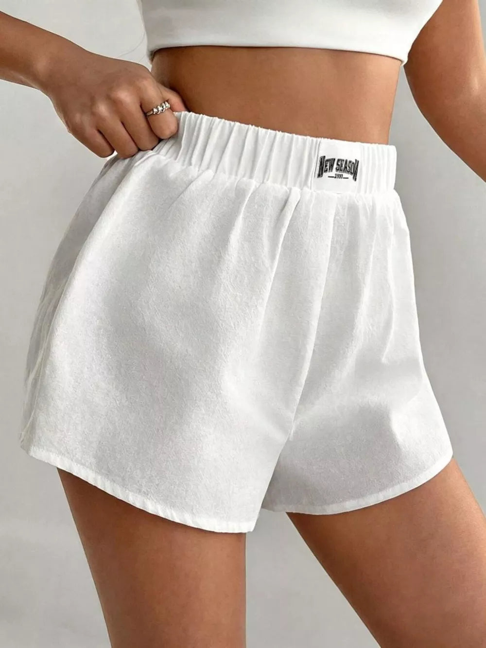 White cotton chino shorts with elastic waistband and logo detail.