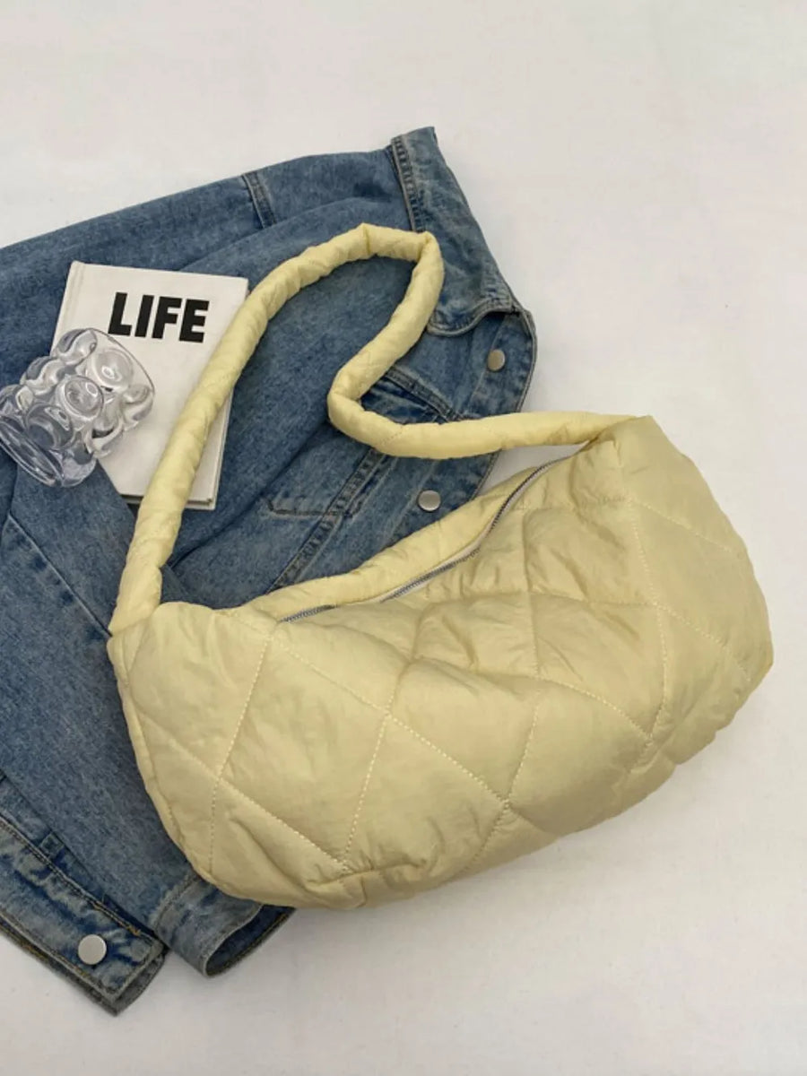 Pastel yellow quilted crossbody bag with a puffy design and a denim jacket.