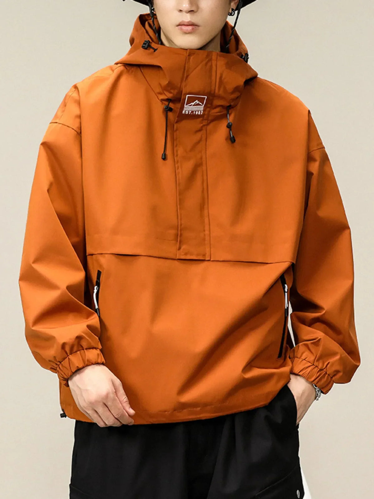 Orange oversized hooded windbreaker jacket with drawstring hood and elastic cuffs.