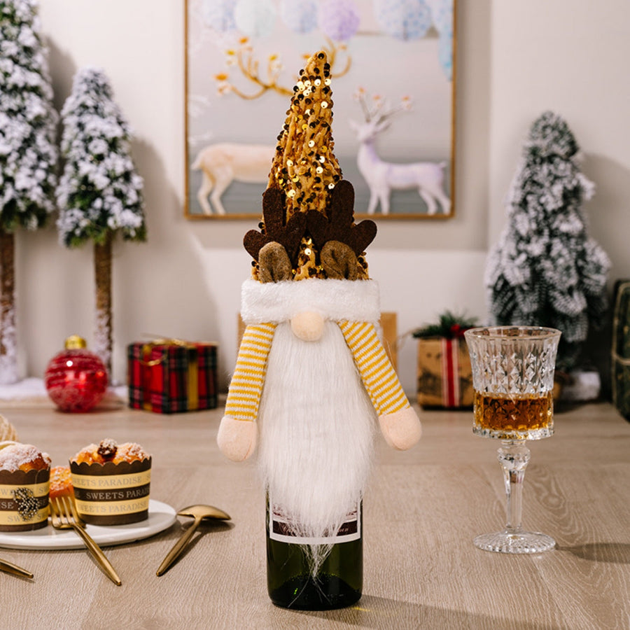Festive gnome bottle topper with gold sequin hat and antlers, white beard, yellow striped sleeves.