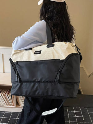 Textured two-tone large duffle bag in black and cream with adjustable strap.