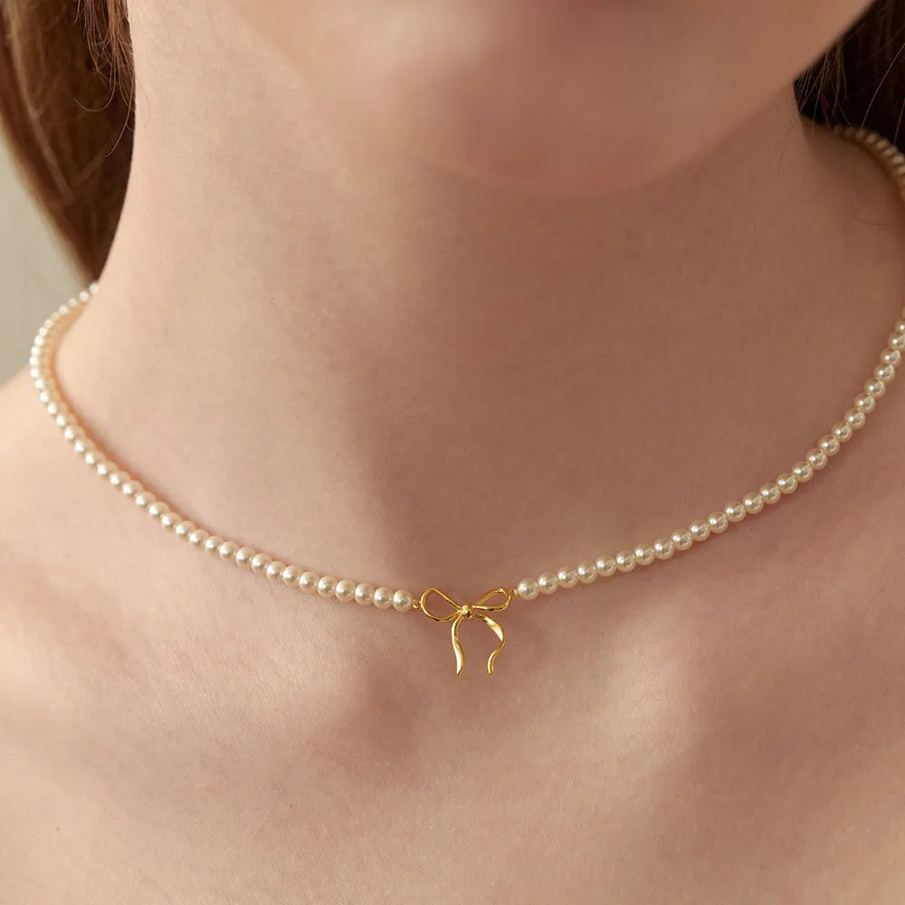Delicate pearl choker necklace with gold bow pendant