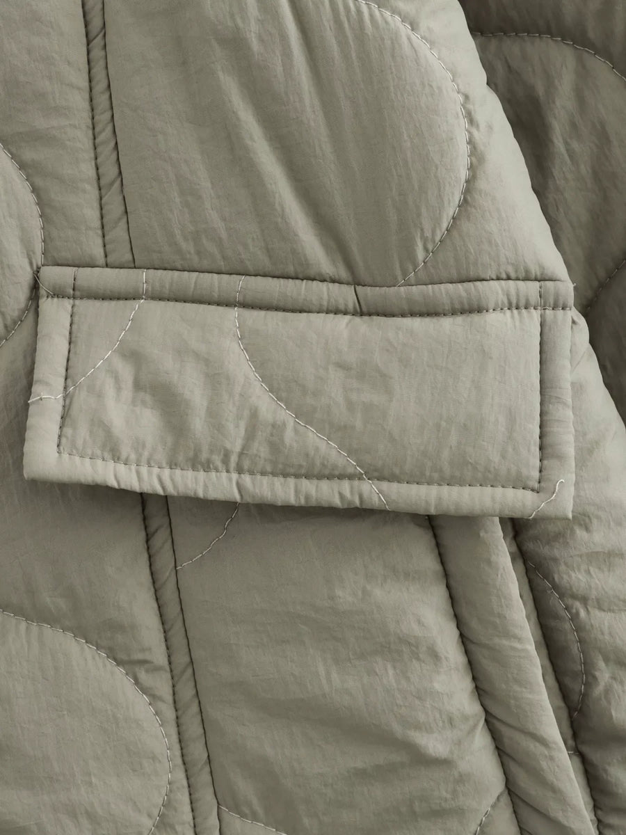 Lined quilted button-down jacket in moss green with a patch pocket and white contrast stitching.
