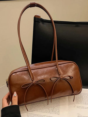 Brown patent leather shoulder bag with bow details and thin straps.