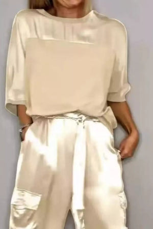Beige satin two-piece outfit set with a crew neck top and belted cargo pants.