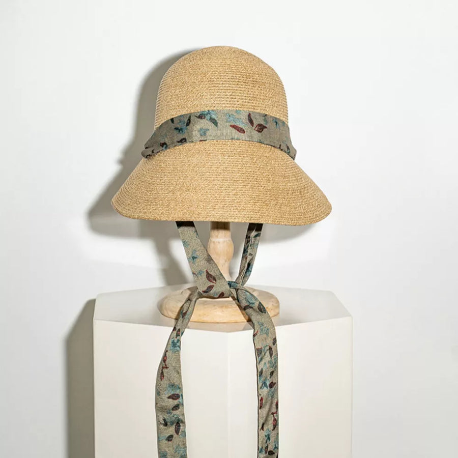Straw sun hat with a floral ribbon and defined crown, tied at the front.