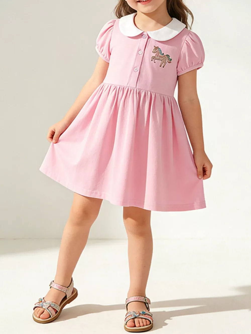Pink cotton toddler dress with unicorn embroidery and white collar.