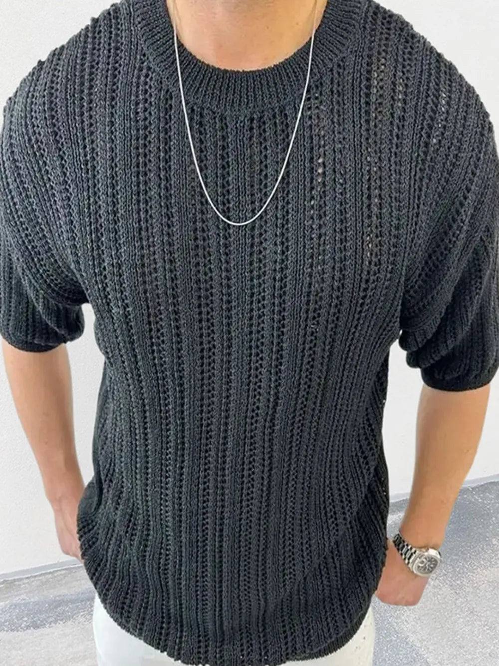 Open-knit boxy crew neck sweater in black acrylic with short sleeves.