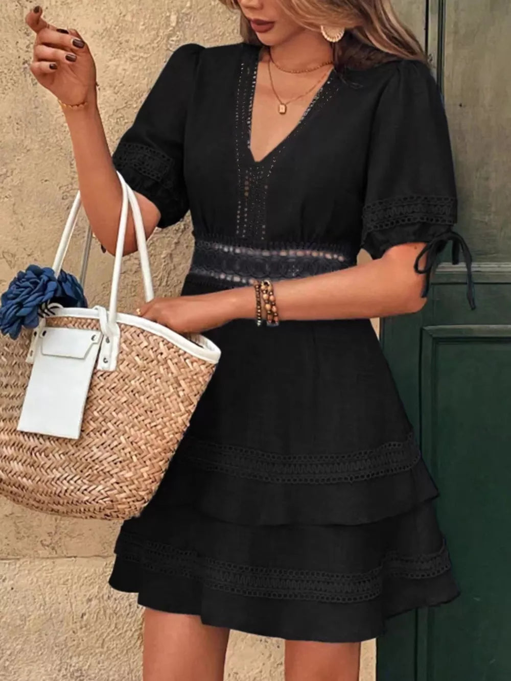 Black lace-embellished V-neck mini dress with tiered skirt and tie sleeves.