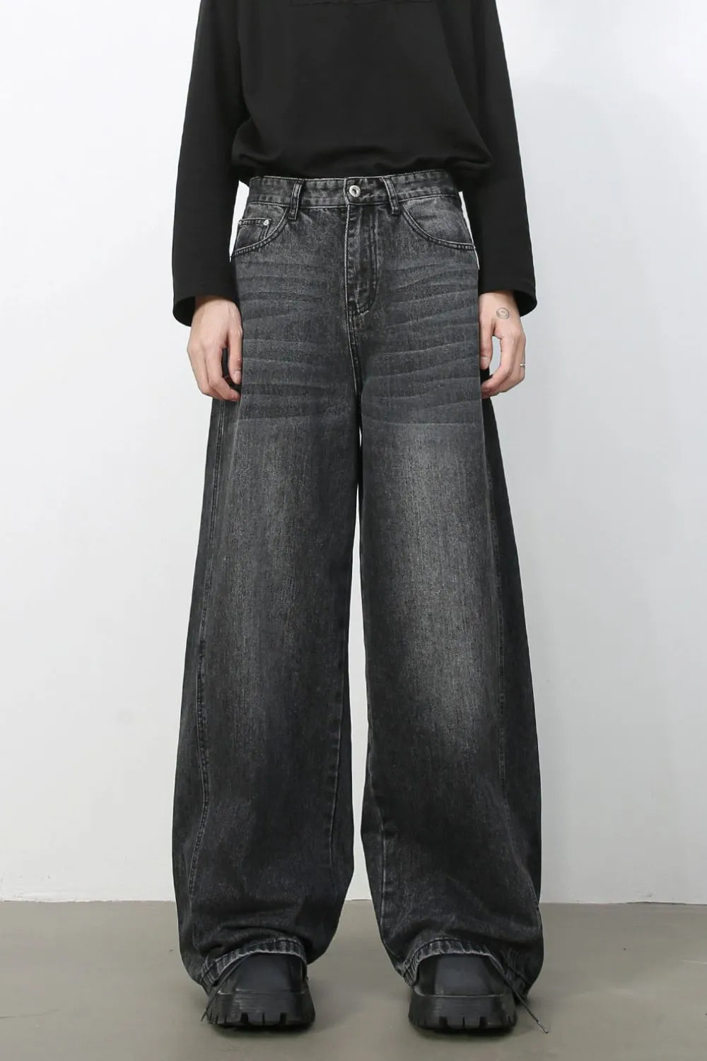 Dark wash denim trousers with exaggerated wide legs and a relaxed fit.