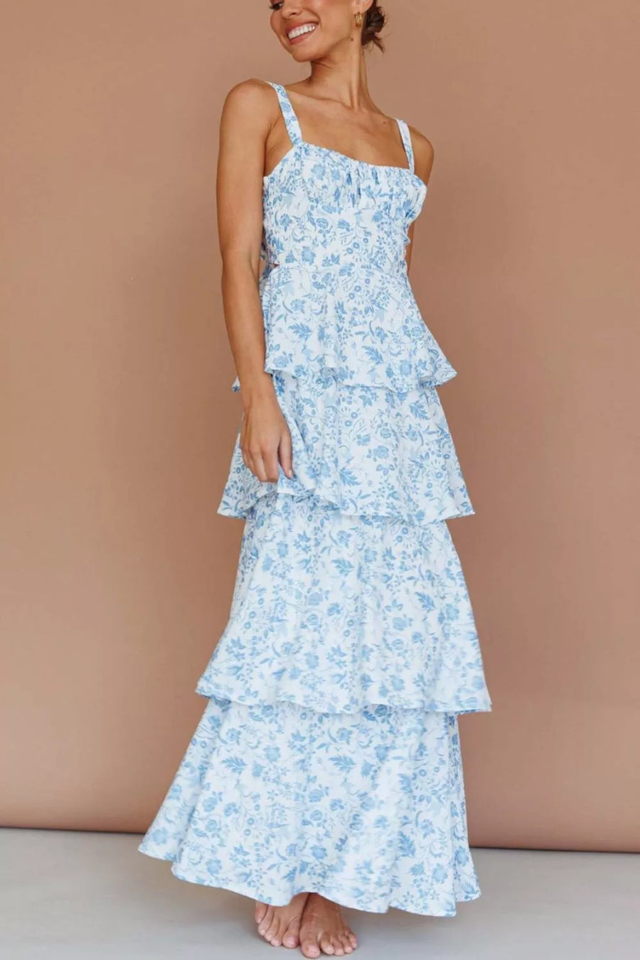 Tiered maxi dress with blue floral print, square neckline, and spaghetti straps.