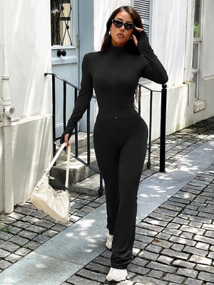Black zippered activewear set with thumbhole sleeves and flared pants.