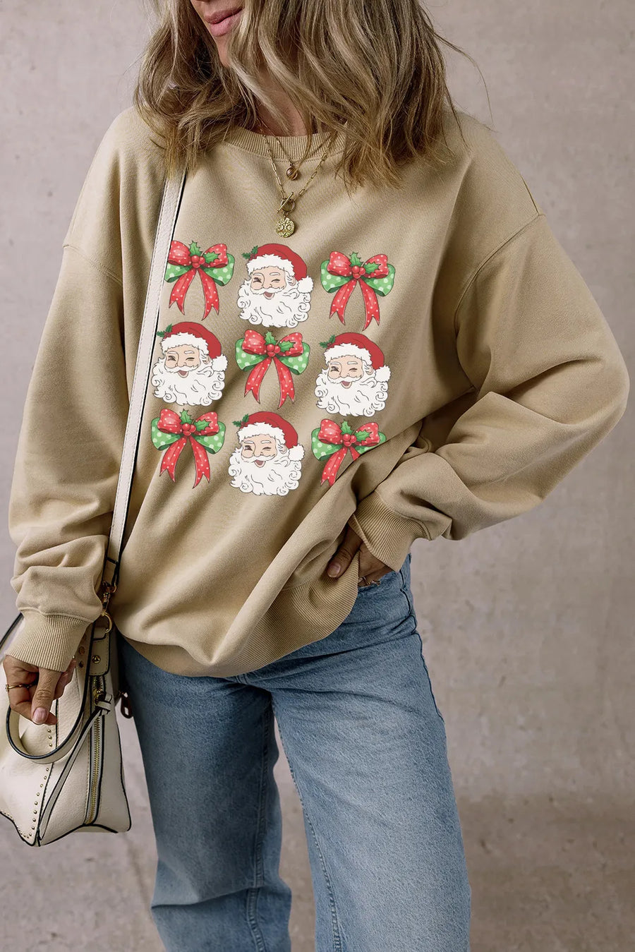 Khaki cotton crewneck sweatshirt with a grid of Santa faces and festive bows graphic.