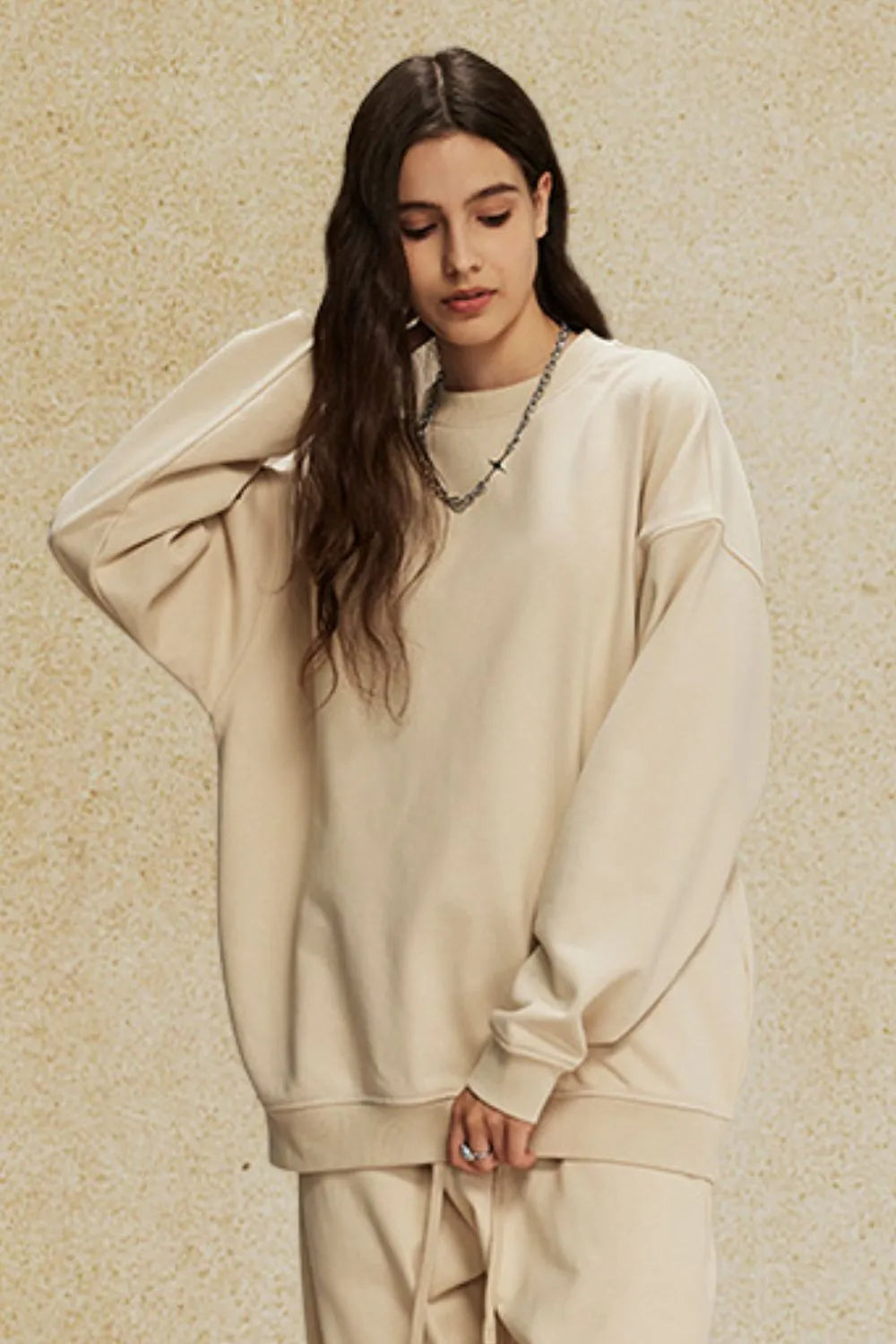 Oversized tan crewneck sweatshirt with subtle shoulders and crew neckline.