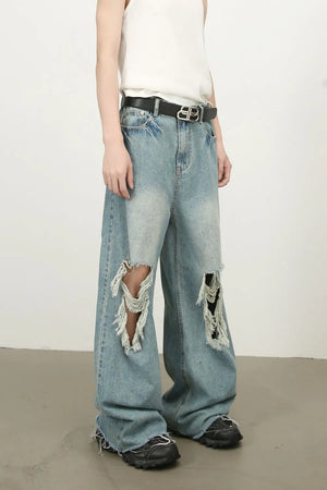 Distressed wide-leg denim jeans in medium wash with fraying and ripped details.