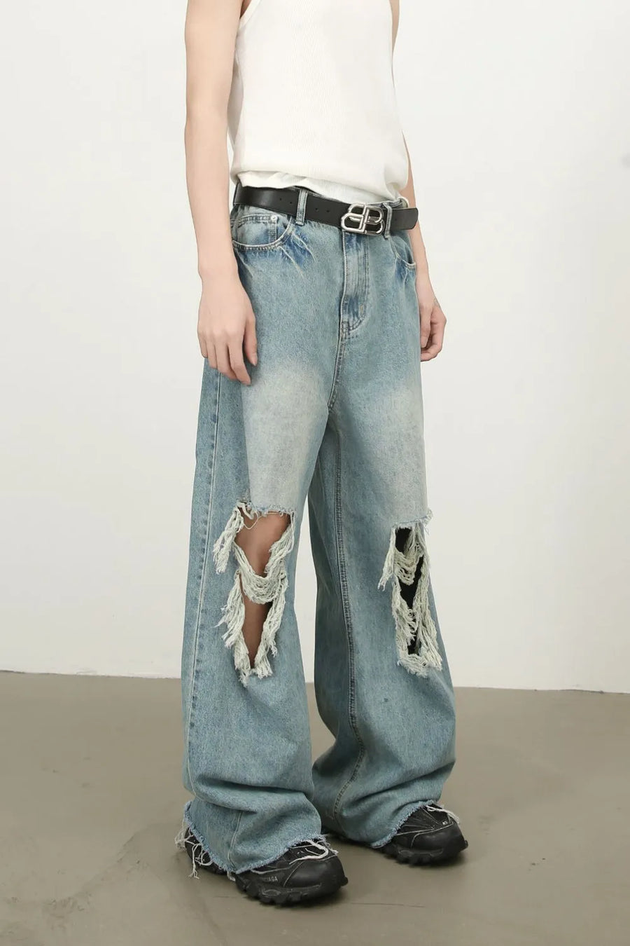 Distressed wide-leg denim jeans in medium wash with fraying and ripped details.