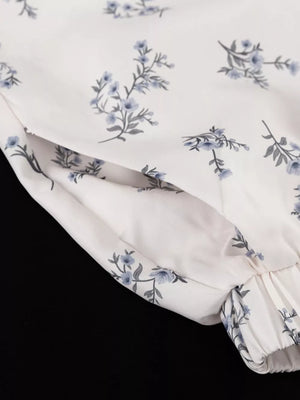 White floral print blouse with blue flowers and a gathered cuff.