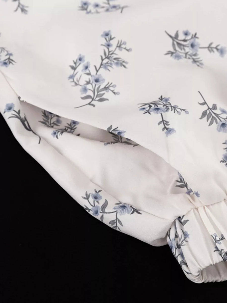 White floral print blouse with blue flowers and a gathered cuff.
