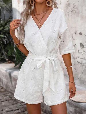 White eyelet wrap romper with tie waist and short sleeves.