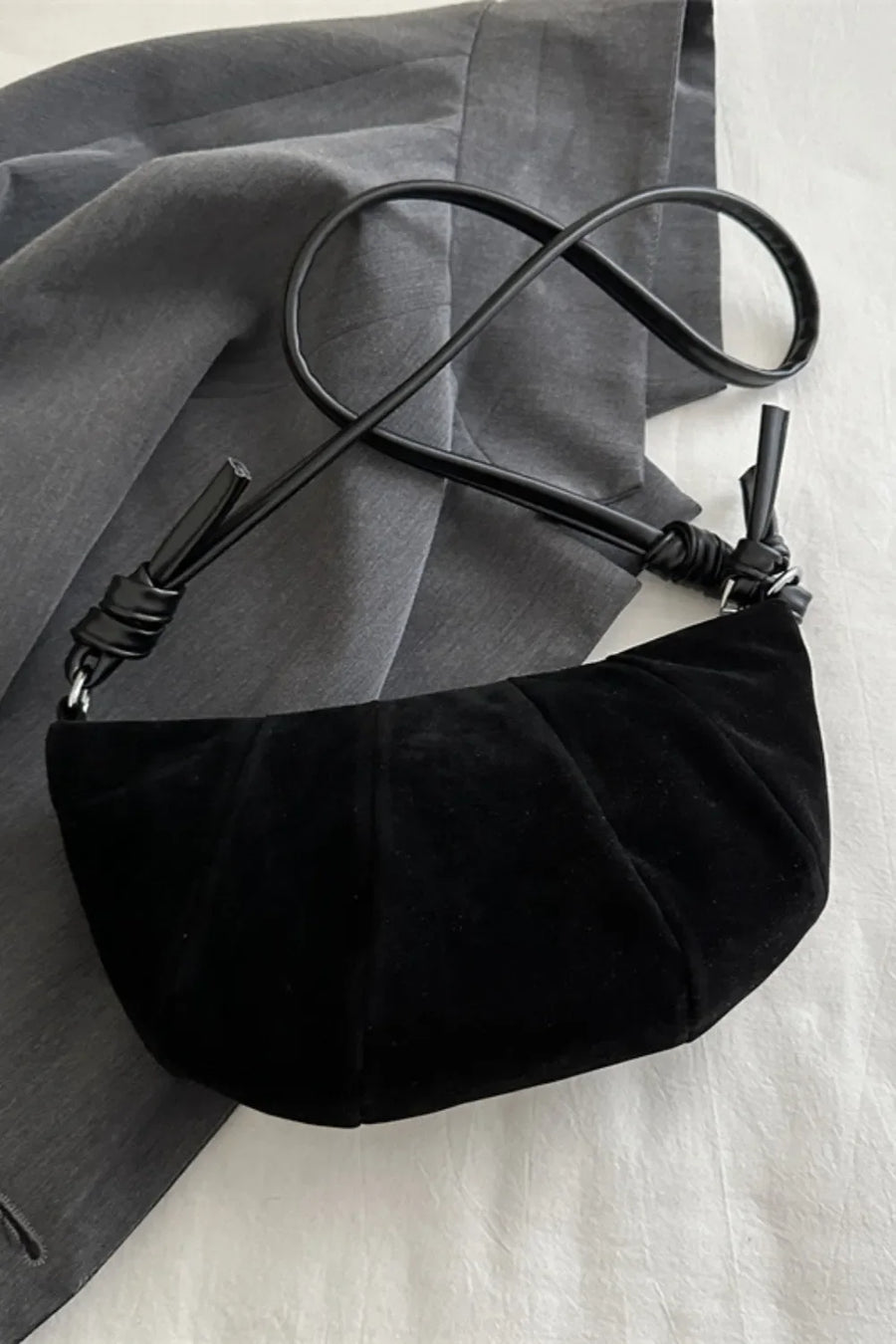 Black pleated suede crescent shoulder bag with knotted strap detail