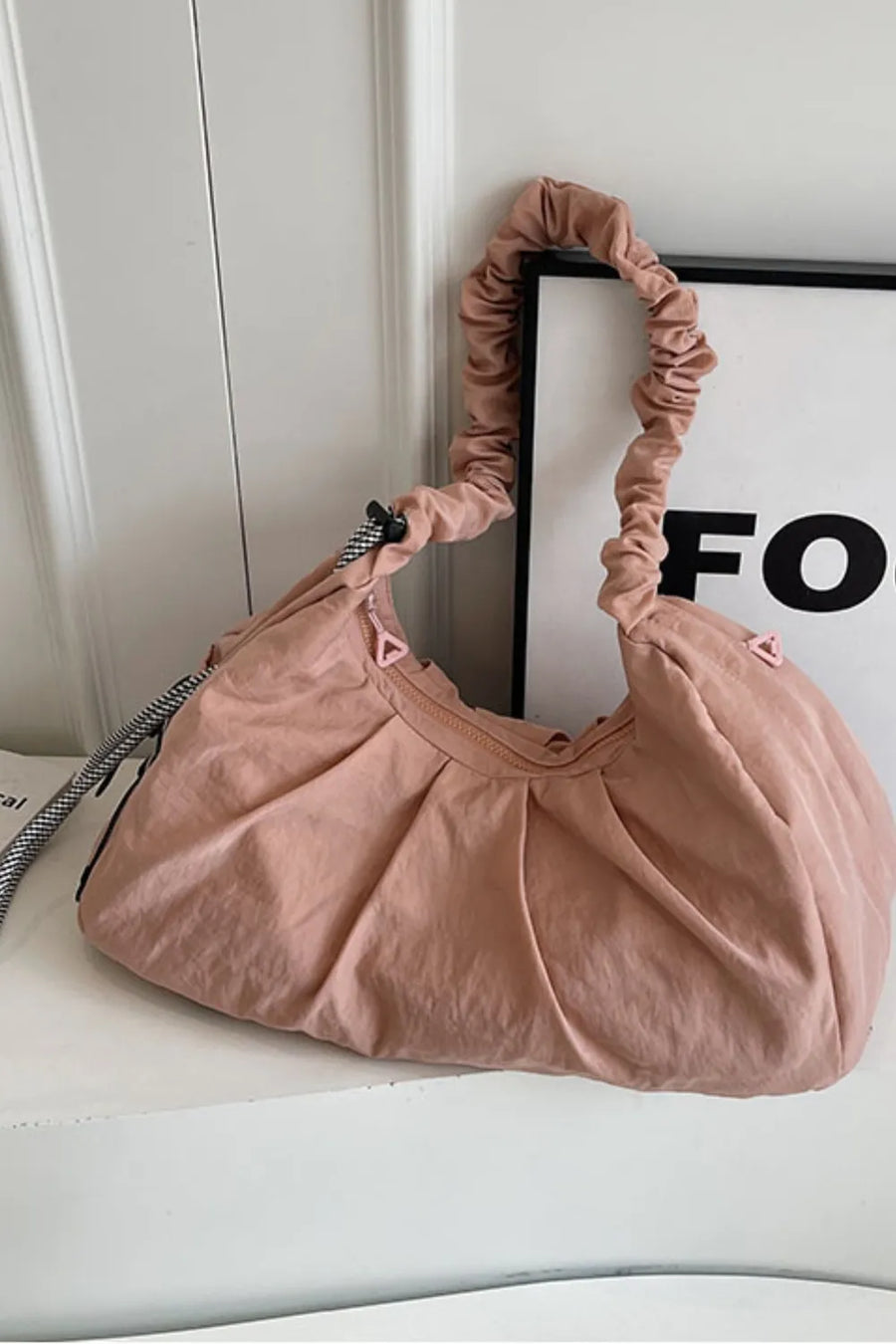 Gathered crescent shoulder bag in pink with ruched strap and pleated detail