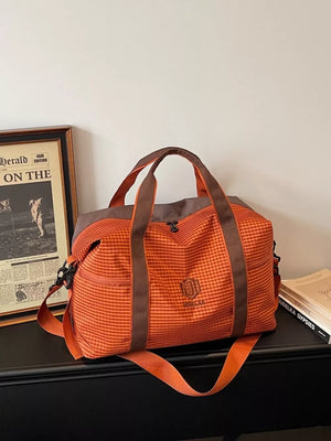 Large orange plaid Oxford travel bag with brown straps and logo