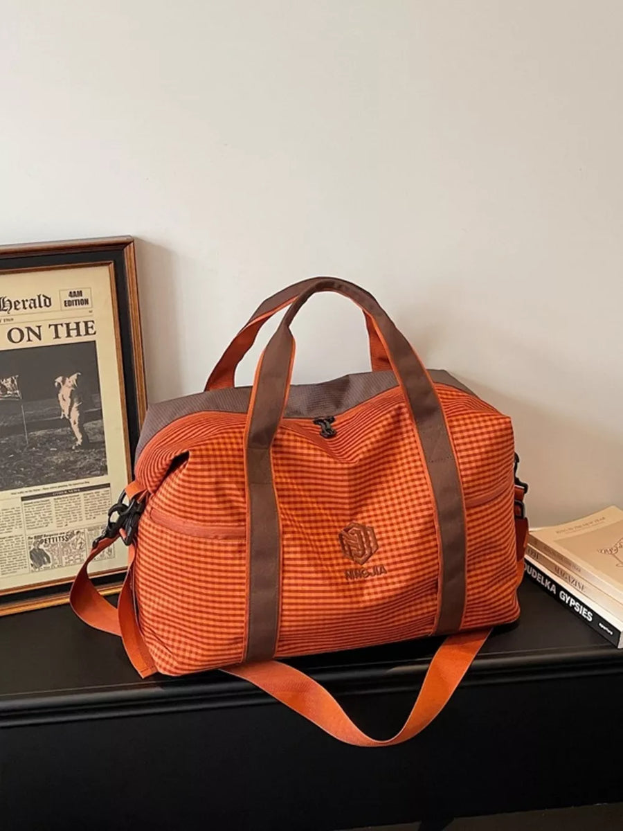 Large orange plaid Oxford travel bag with brown straps and logo