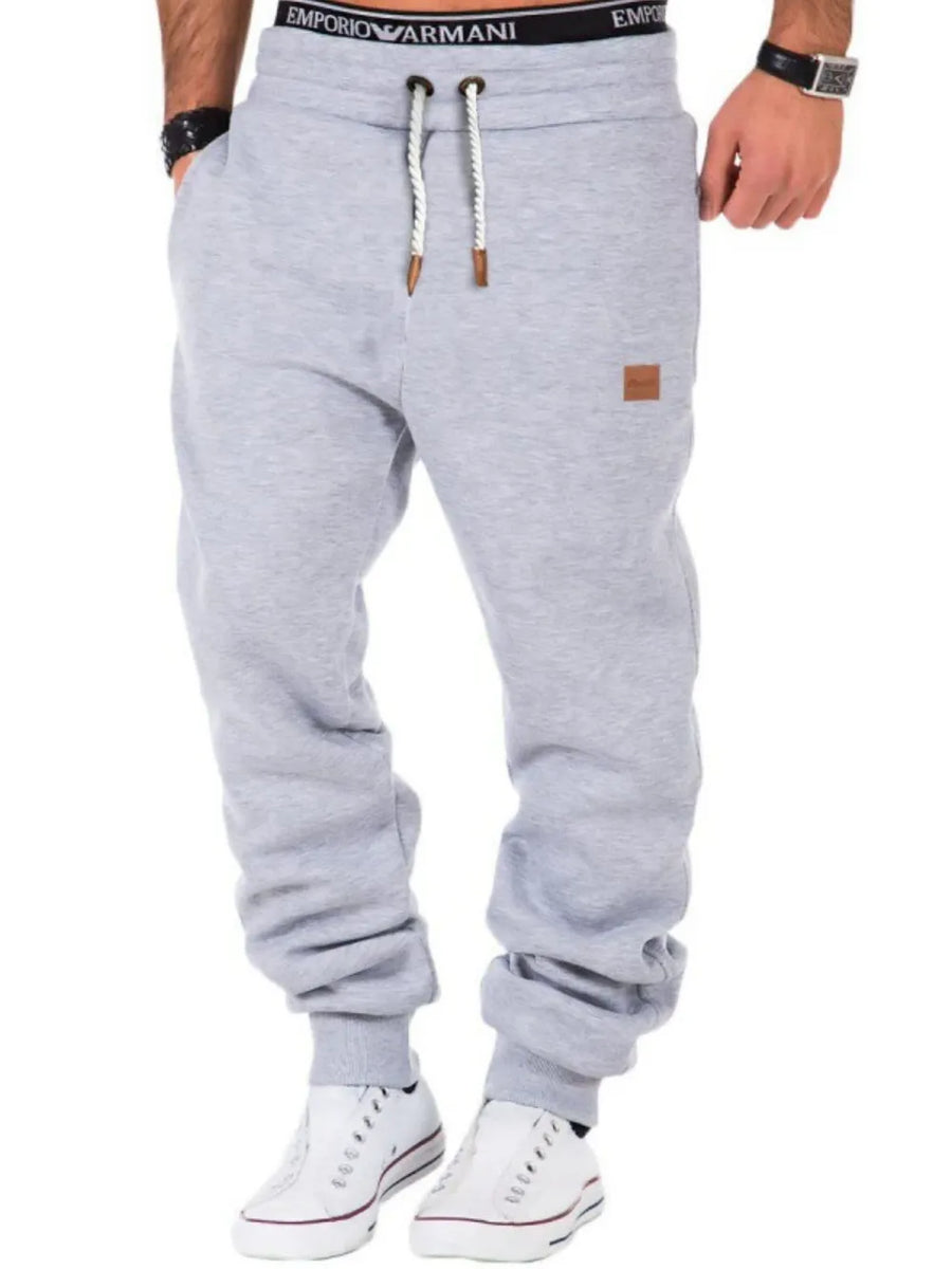 Gray relaxed fit joggers with drawstring and leather detail on pocket.