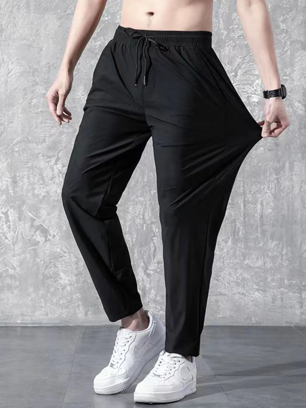 Black relaxed-fit drawstring trousers with elastic waistband and adjustable tie.