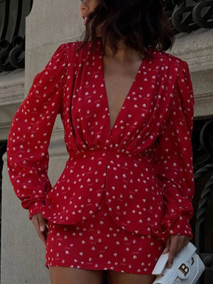 Red printed mini dress with deep V-neck, long sleeves, and peplum detail.