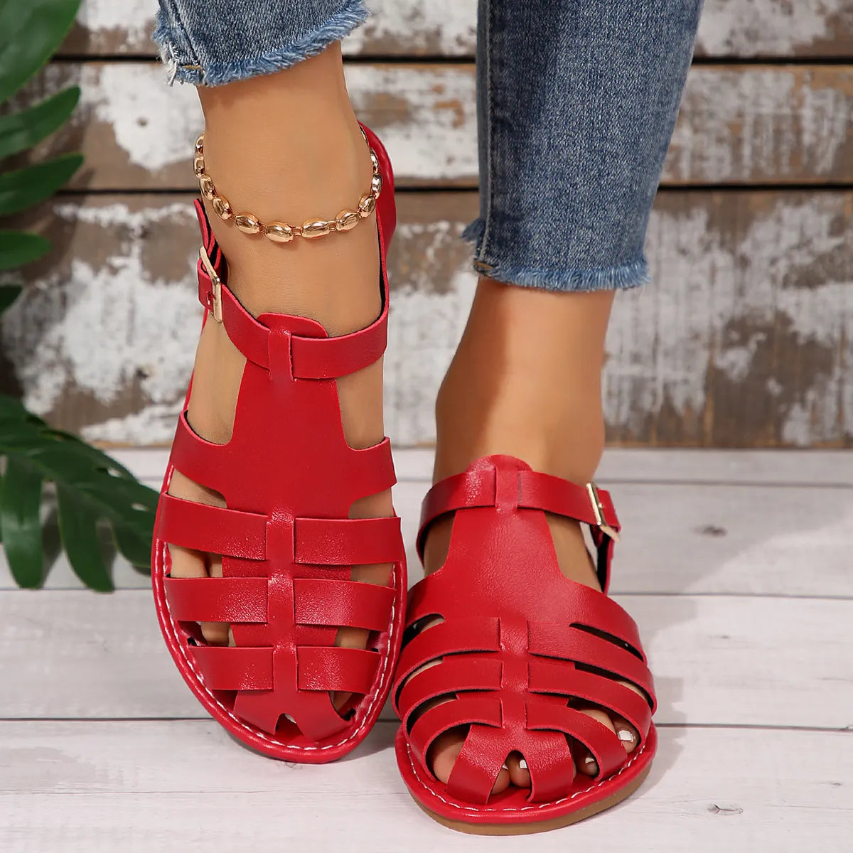 Red woven leather t-strap sandals with ankle strap and buckle closure.