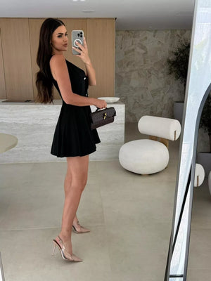 Black double-breasted mini dress with pleats and gold buttons, sleeveless, V-neck.