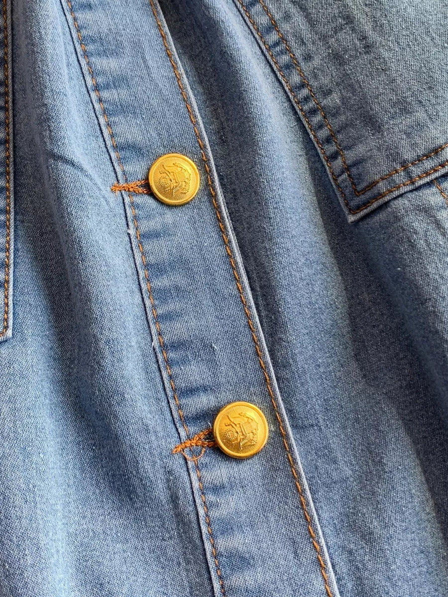 Light blue denim dress with gold button detail and contrast stitching.