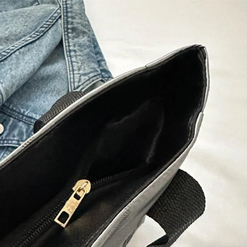 Silver padded nylon tote bag interior with zipper detail and black straps.