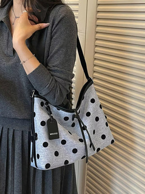 black handbag featuring shoulder strap and polka dot