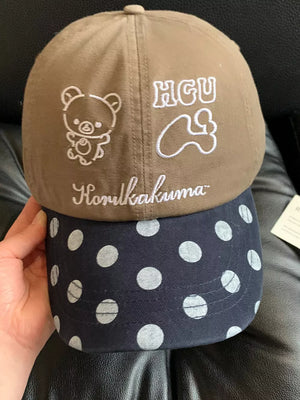 Baseball cap with brown top and navy polka dot brim, featuring Rilakkuma embroidery.