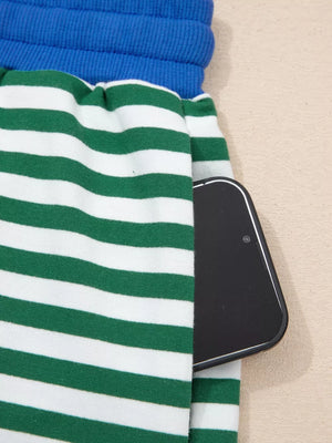 Green and white striped cotton shorts with blue waistband and side pocket holding a phone.