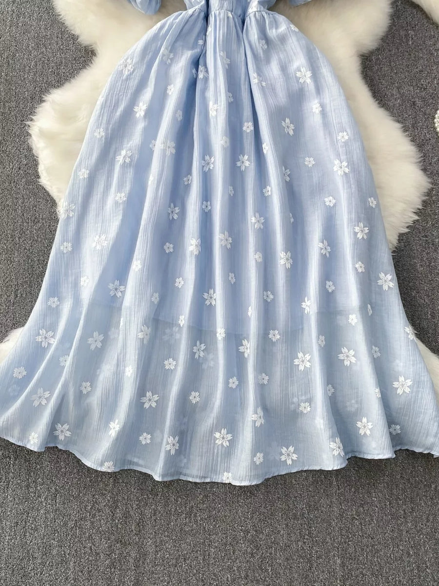 Light blue midi dress with white floral embroidery and puff sleeves.