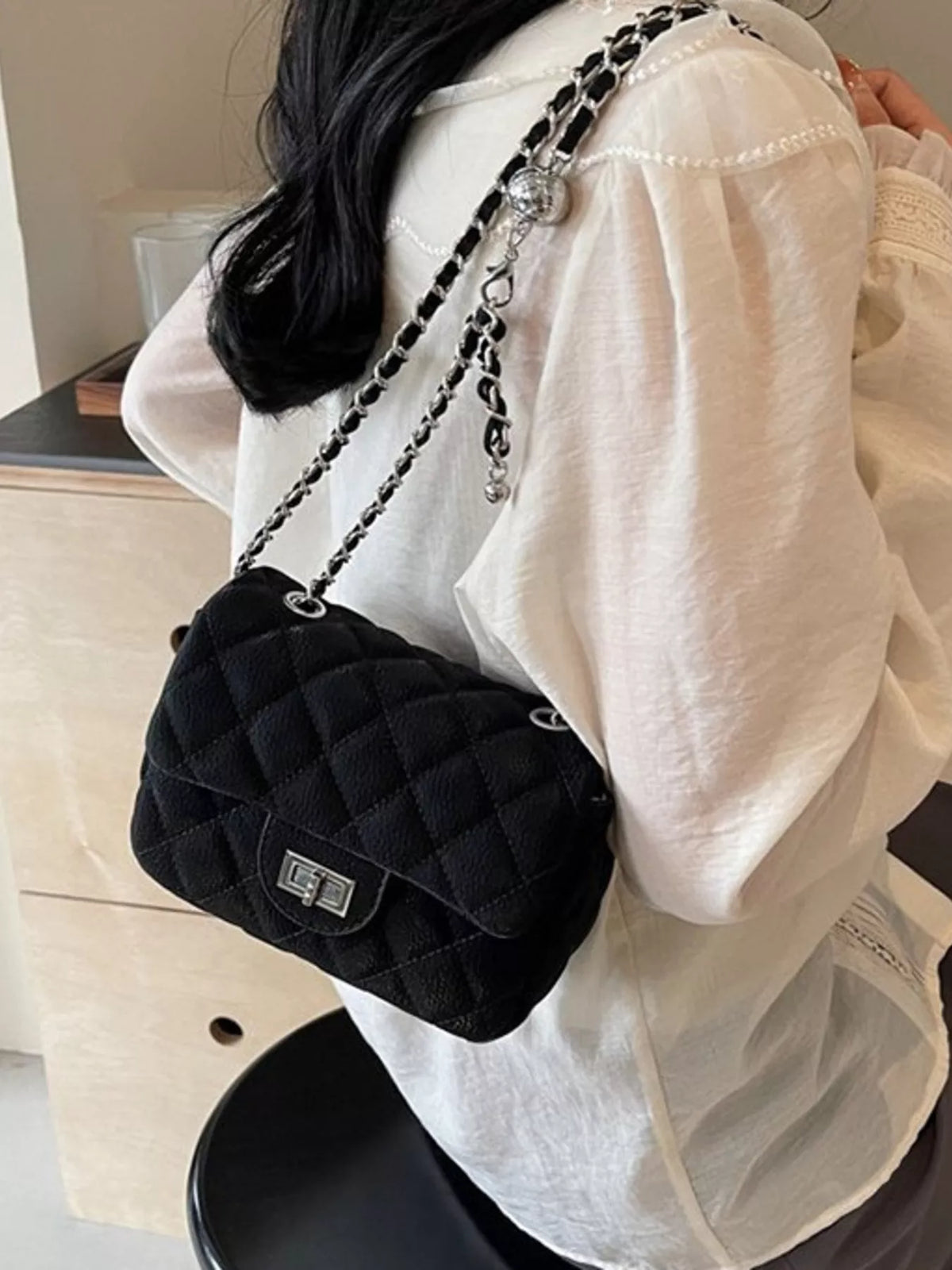 Black quilted chain crossbody clutch with silver hardware and a turn-lock closure.