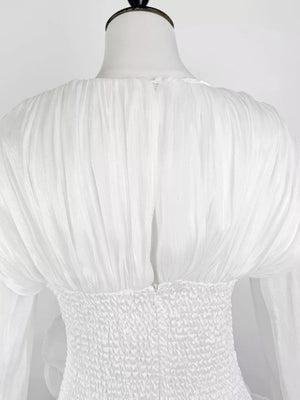 White cotton mini dress with ruched bodice and voluminous ruffled sleeves.