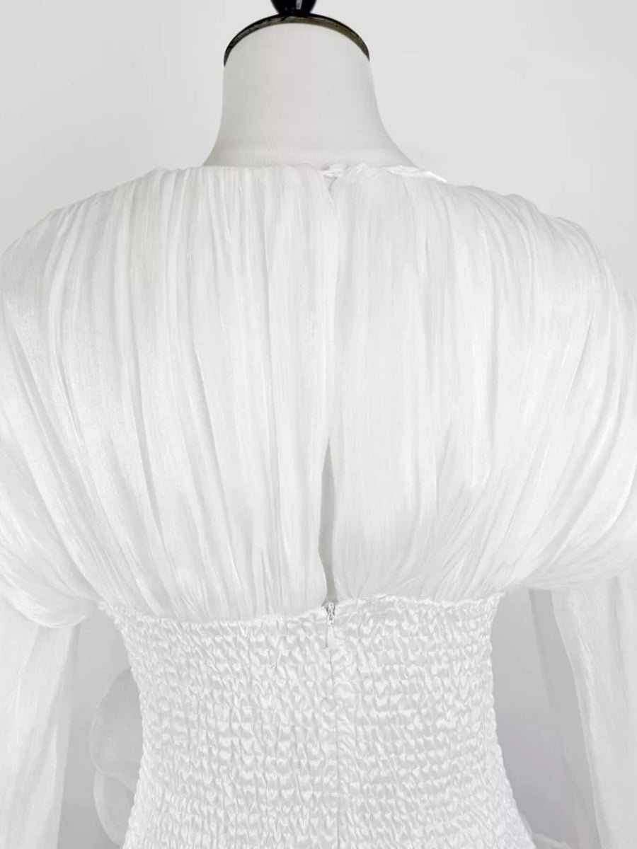 White cotton mini dress with ruched bodice and voluminous ruffled sleeves.