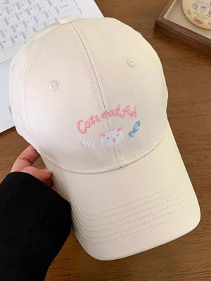 Cream baseball cap with embroidered cat and fish design and text.